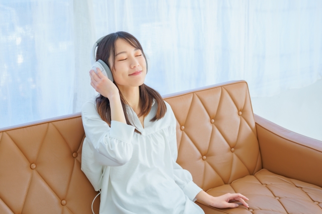 ソファでゆっくり音楽を聴く女性
